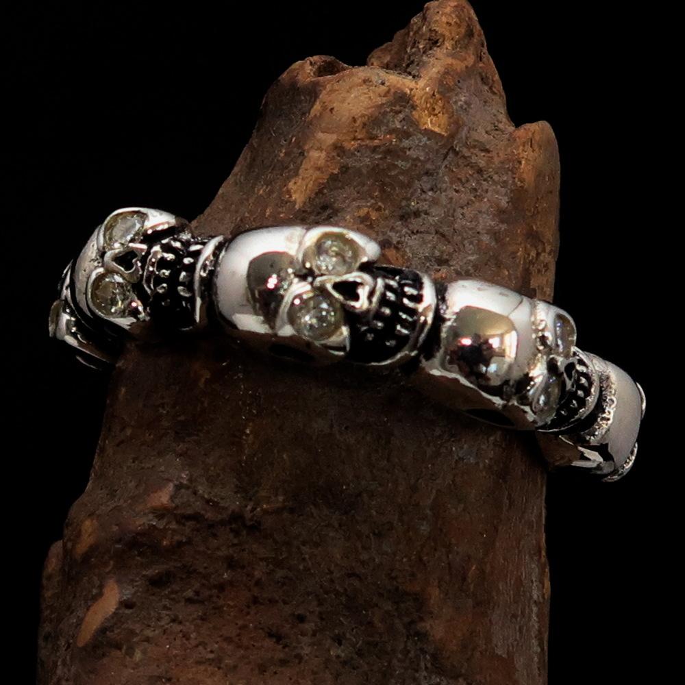 Men's sterling silver band ring featuring 6 small skulls with white cubic zirconia eyes, showcasing a polished and antiqued finish.