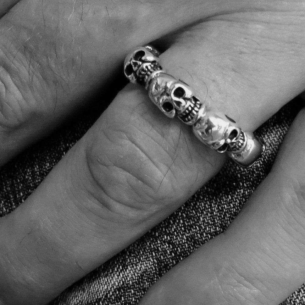 Men's sterling silver band ring featuring 6 small skulls with white cubic zirconia eyes, showcasing a polished and antiqued finish.