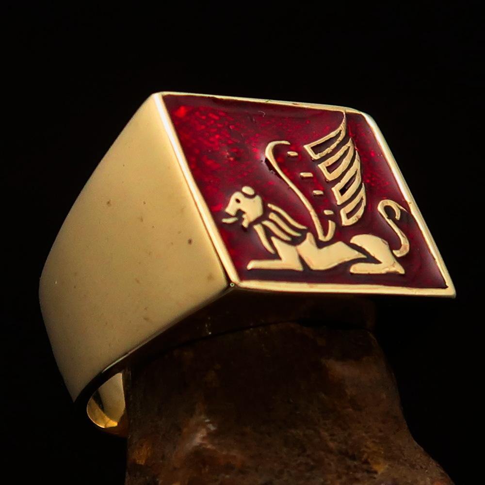 Solid brass men's ring featuring a winged lion design with vibrant red enamel finish, symbolizing strength and power.