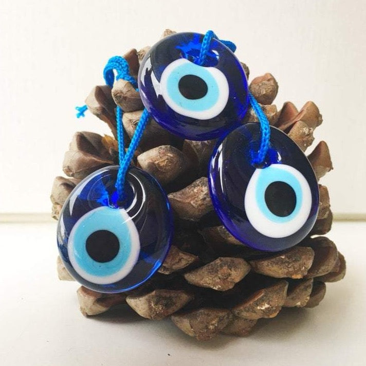A beautiful handmade blue glass evil eye bead charm, symbolizing protection and good luck, perfect for car or home decor.