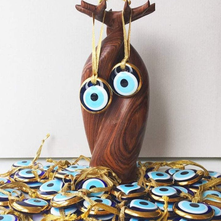 A beautiful gold trimmed glass evil eye bead, featuring a vibrant blue center, perfect for wedding favors and home decor.