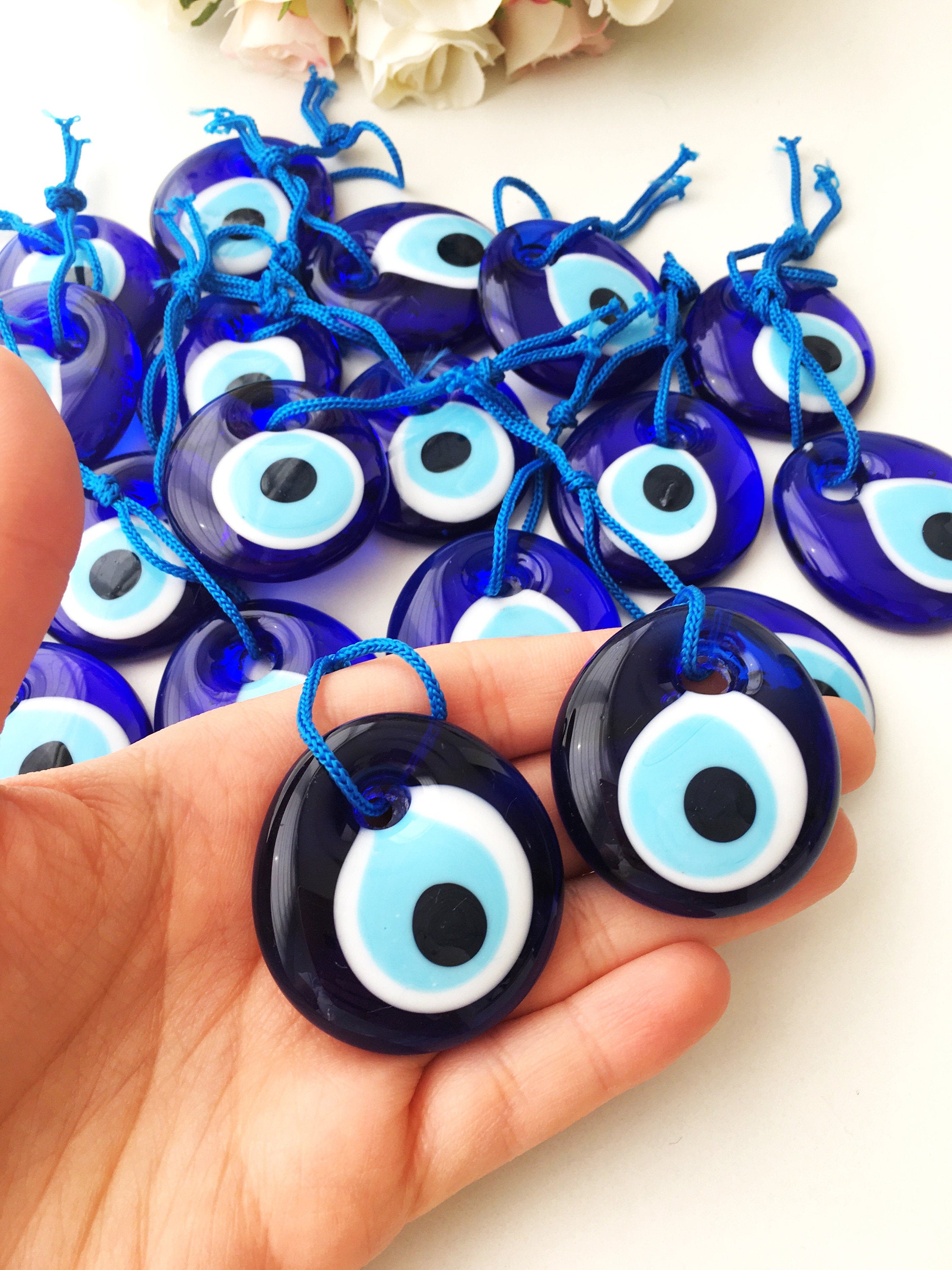 A collection of 100 blue glass evil eye charm beads, each 4.5cm, with blue ropes for hanging, symbolizing protection and good luck.