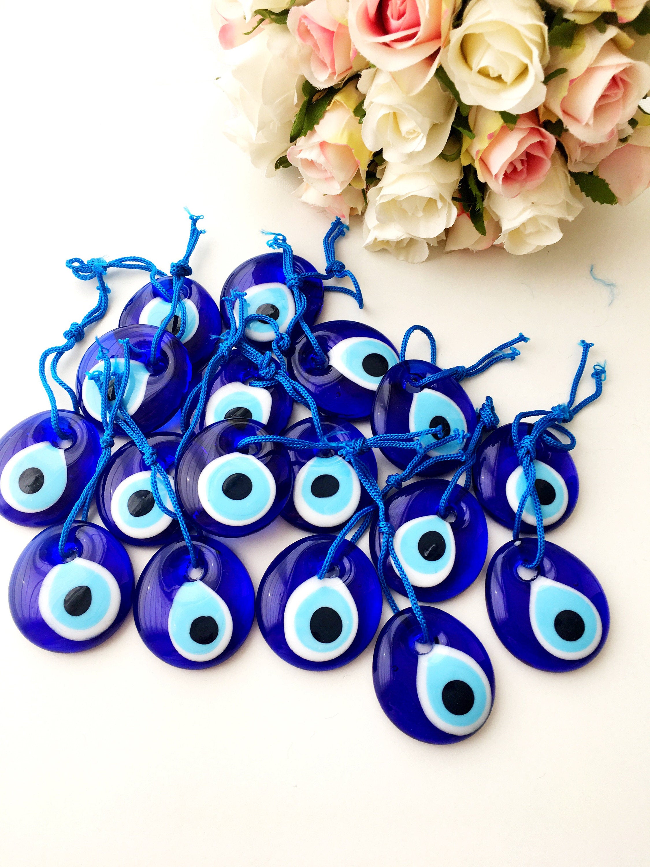 A collection of 100 blue glass evil eye charm beads, each 4.5cm, with blue ropes for hanging, symbolizing protection and good luck.