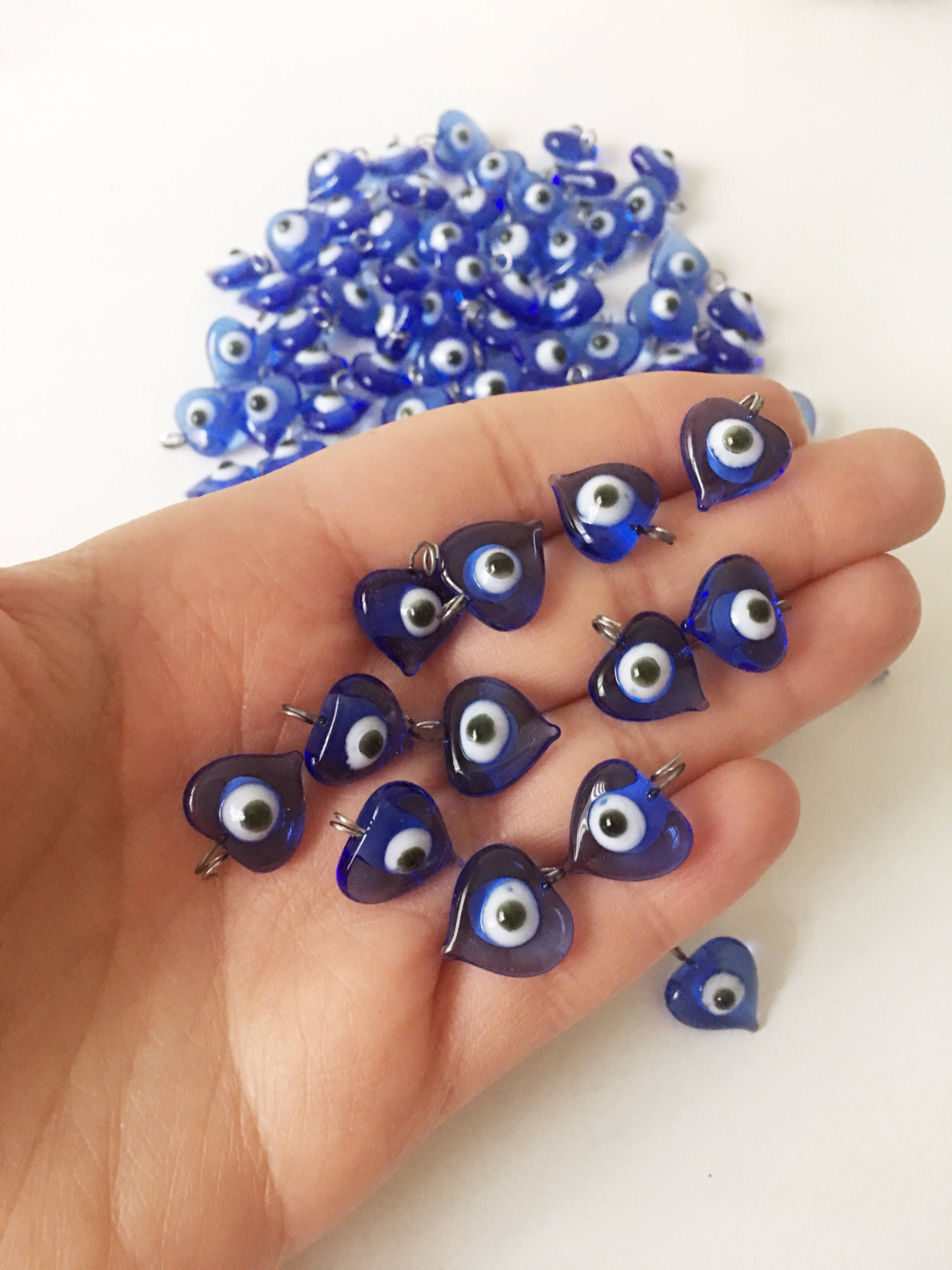 A collection of 10 blue glass evil eye charms with metal hooks, symbolizing protection and good luck, ideal for wedding favors and DIY jewelry.