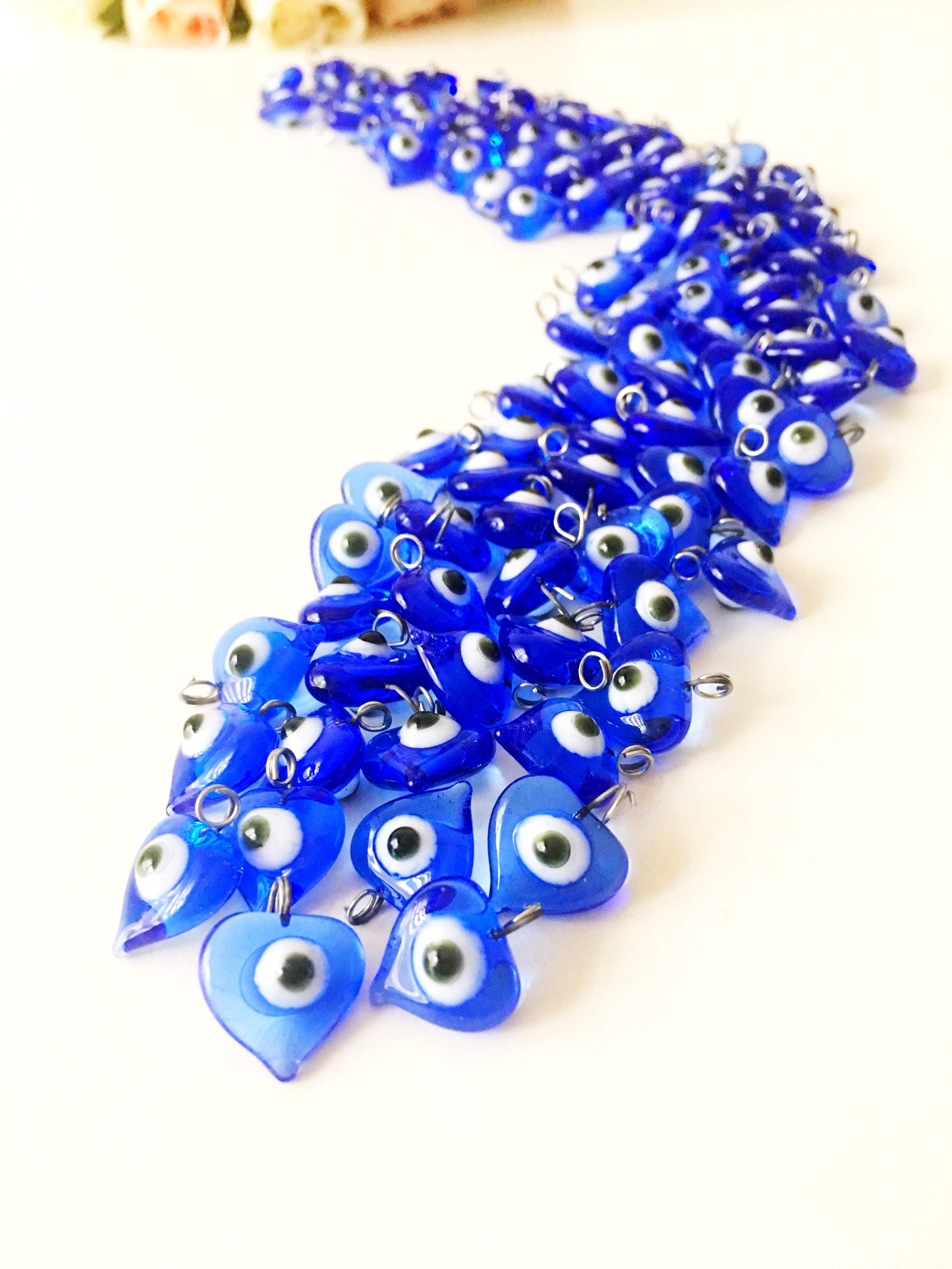 A collection of 10 blue glass evil eye charms with metal hooks, symbolizing protection and good luck, ideal for wedding favors and DIY jewelry.