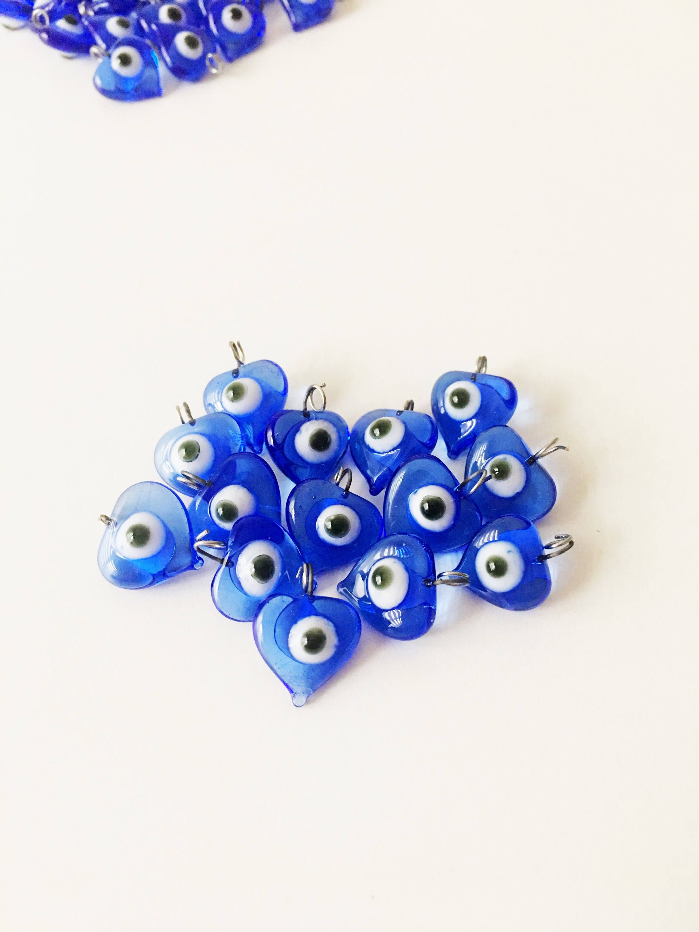 A collection of 10 blue glass evil eye charms with metal hooks, symbolizing protection and good luck, ideal for wedding favors and DIY jewelry.