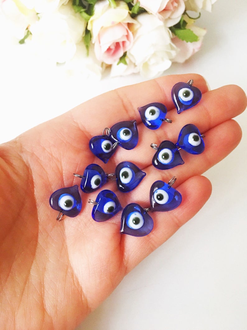 A collection of 100 unique blue evil eye charms with hooks, perfect for wedding favors and DIY jewelry projects.