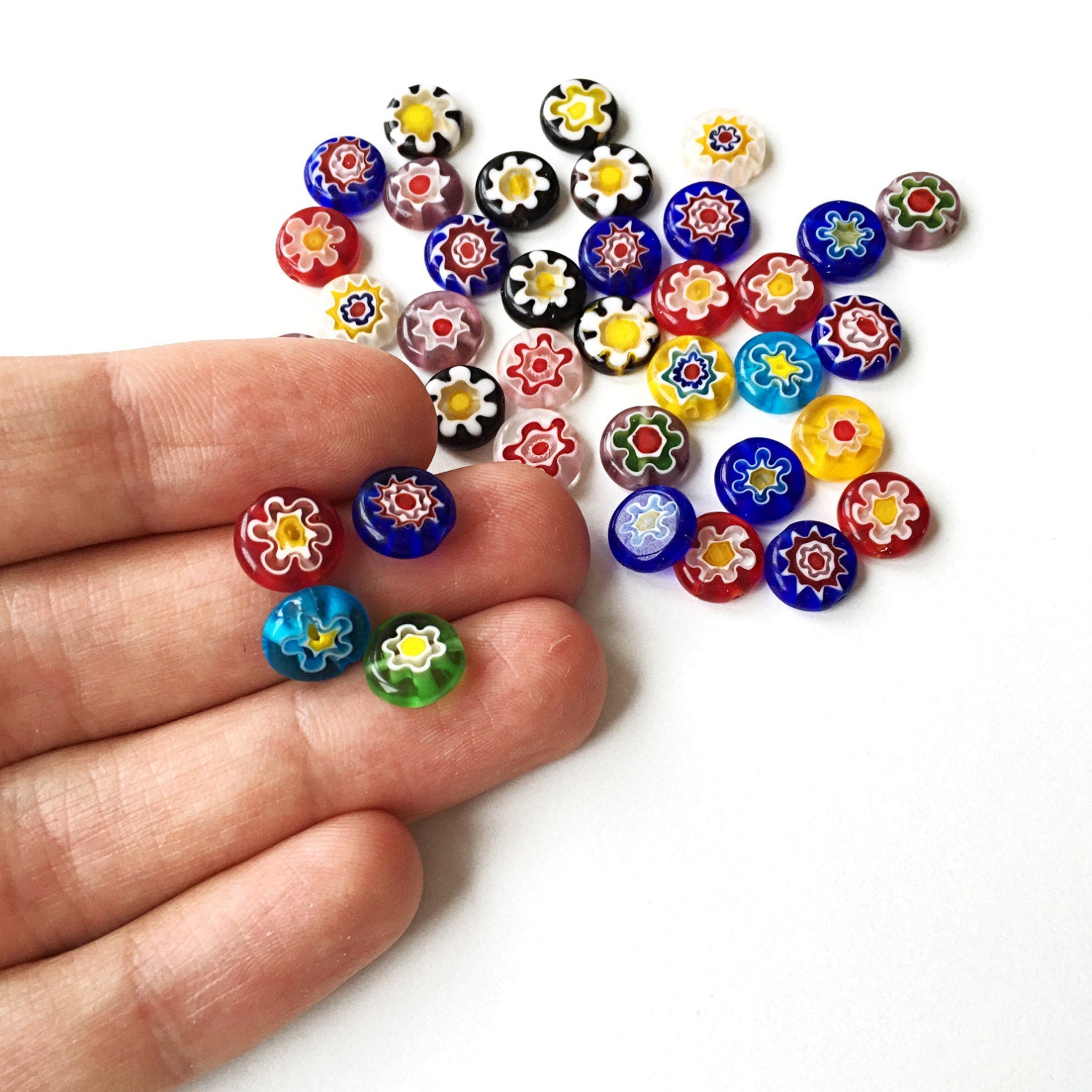A vibrant assortment of 10mm and 8mm millefiori flat coin glass beads featuring floral designs in assorted colors, ideal for jewelry making.