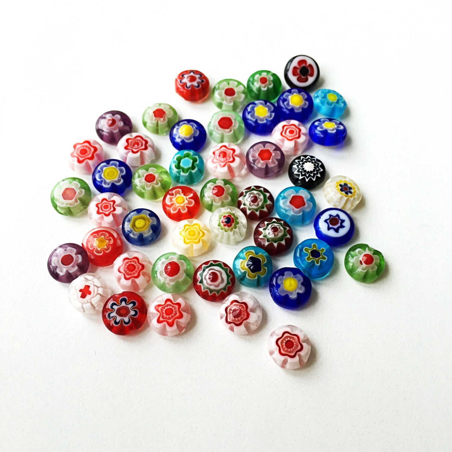 A vibrant assortment of 10mm and 8mm millefiori flat coin glass beads featuring floral designs in assorted colors, ideal for jewelry making.