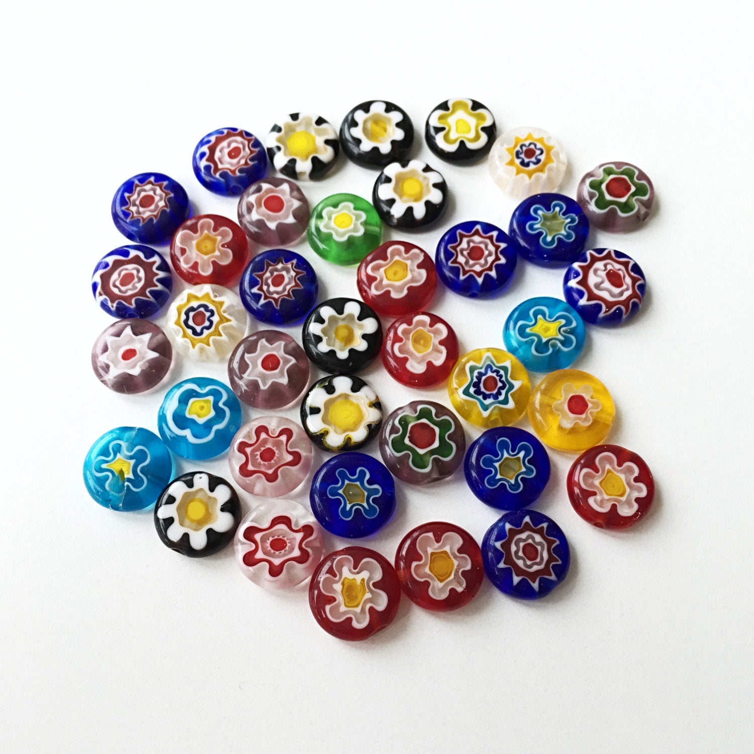 A vibrant assortment of 10mm and 8mm millefiori flat coin glass beads featuring floral designs in assorted colors, ideal for jewelry making.
