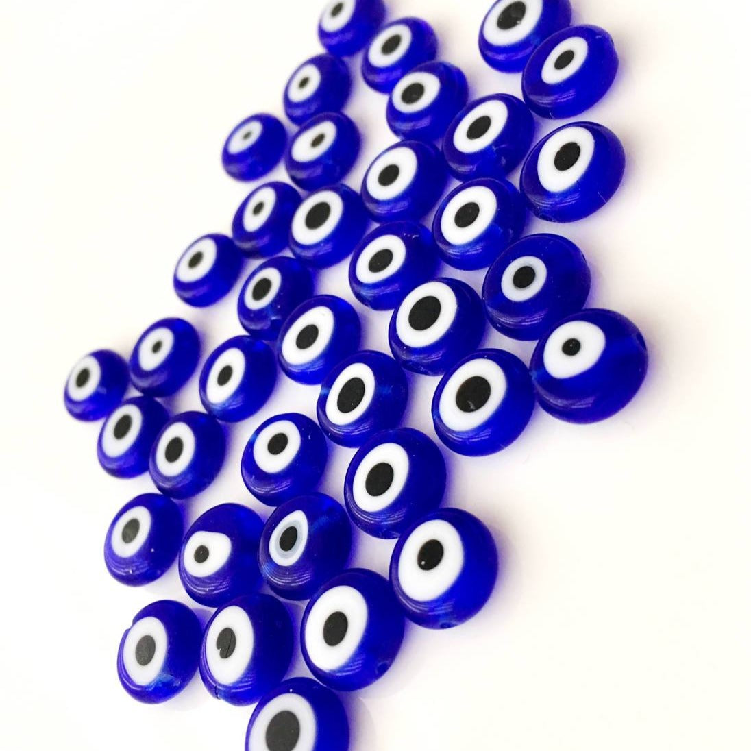 A collection of 120 blue glass evil eye beads in various sizes from 6mm to 12mm, showcasing their unique handmade designs.