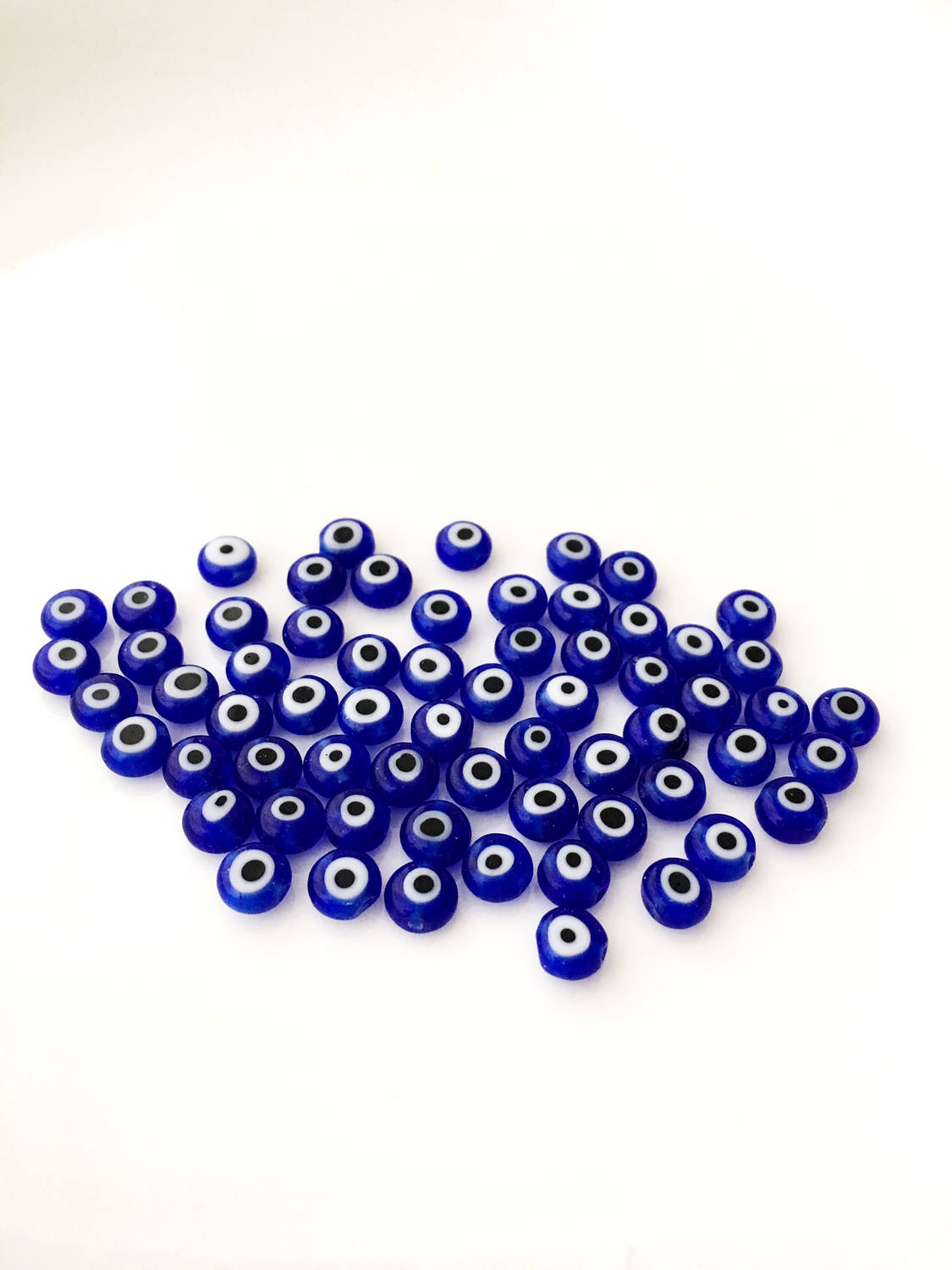 A collection of 120 blue glass evil eye beads in various sizes from 6mm to 12mm, showcasing their unique handmade designs.