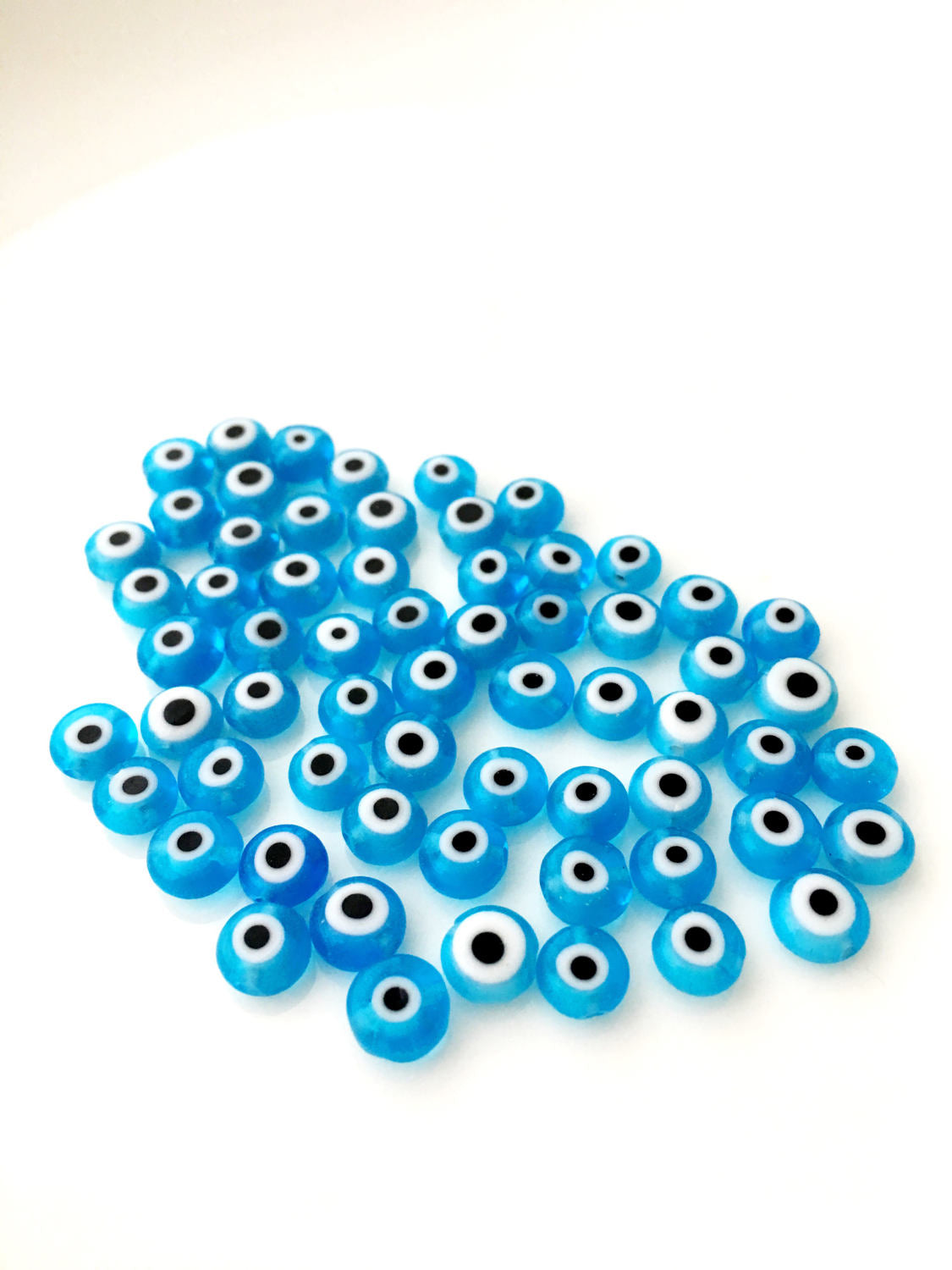 A collection of 120 turquoise glass evil eye beads in various sizes from 6mm to 12mm, showcasing their unique handmade designs.