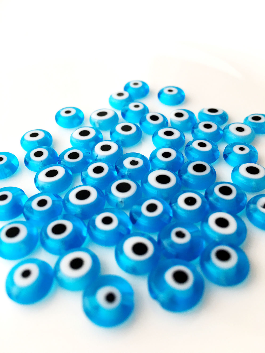 A collection of 120 turquoise glass evil eye beads in various sizes from 6mm to 12mm, showcasing their unique handmade designs.
