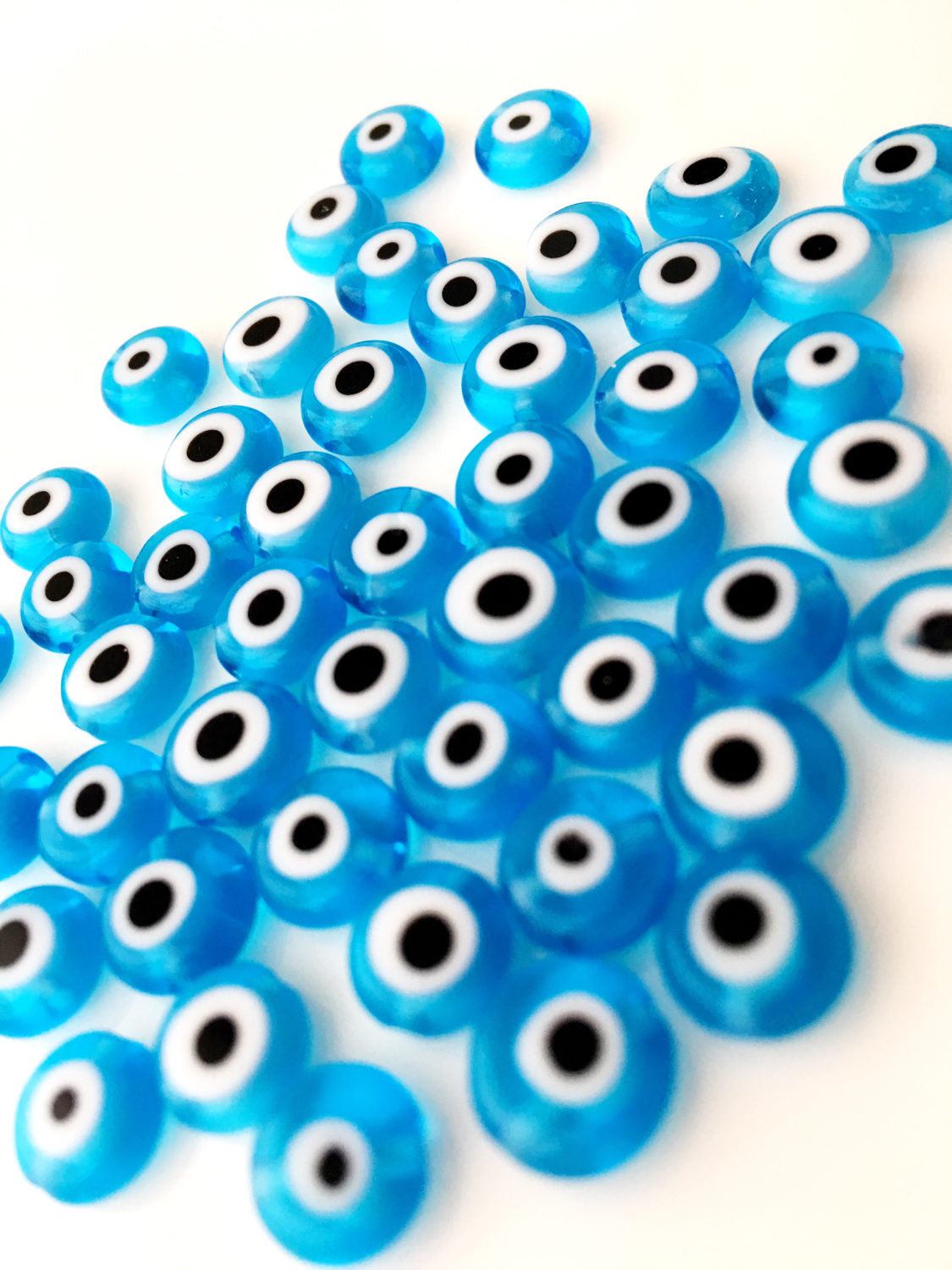A collection of 120 turquoise glass evil eye beads in various sizes from 6mm to 12mm, showcasing their unique handmade designs.