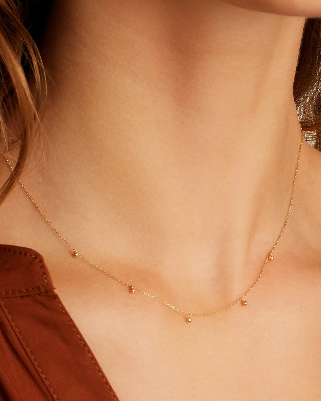 Elegant 14k Gold Newport Flutter Necklace with dainty beads on an adjustable chain, showcasing its intricate design.