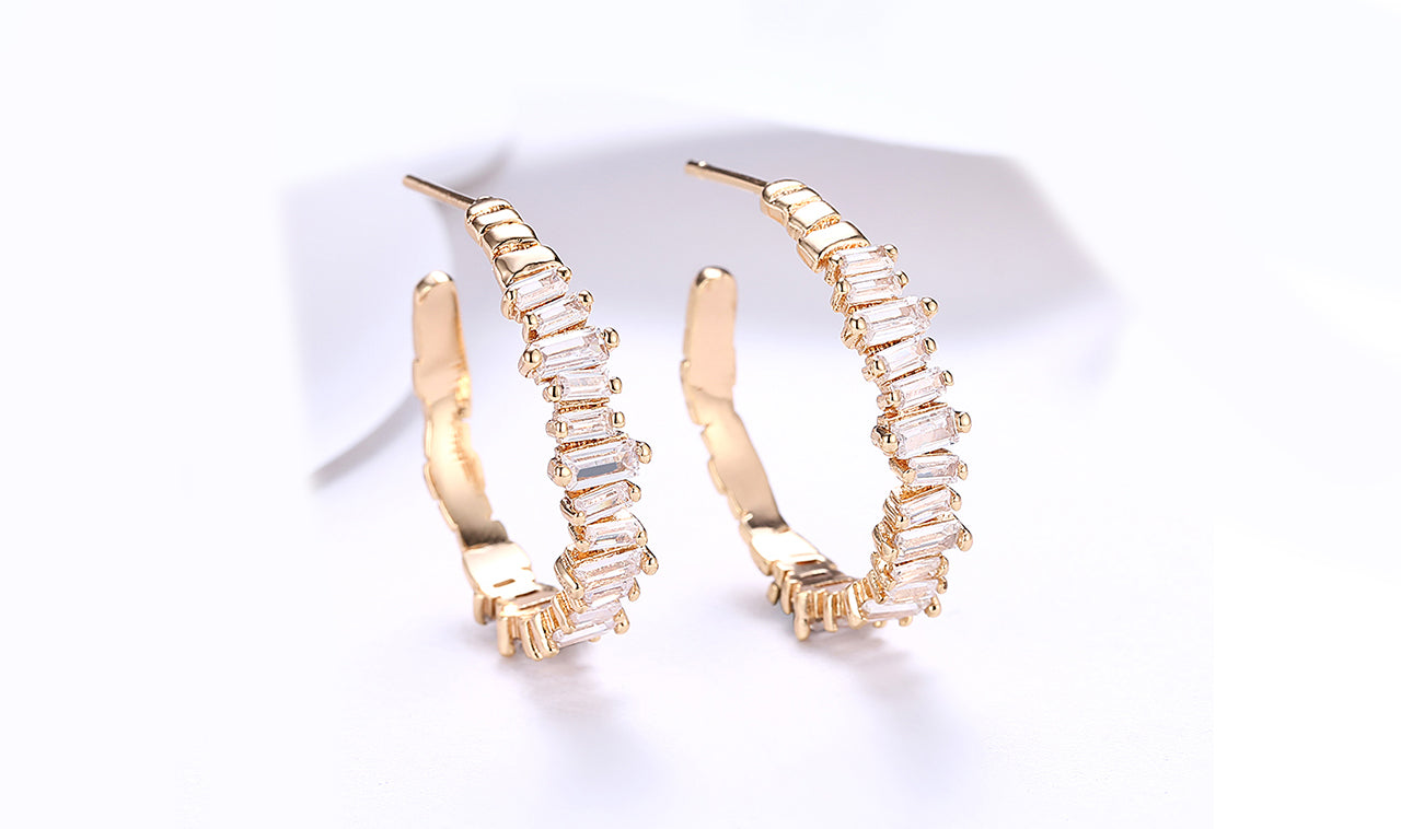 Elegant 14K gold plated asymmetrical earrings featuring emerald cut white elements stones, showcasing a modern design.