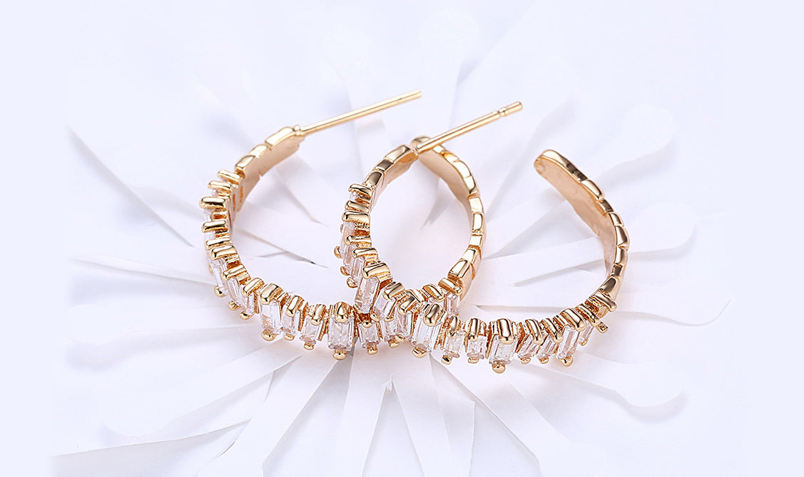 Elegant 14K gold plated asymmetrical earrings featuring emerald cut white elements stones, showcasing a modern design.