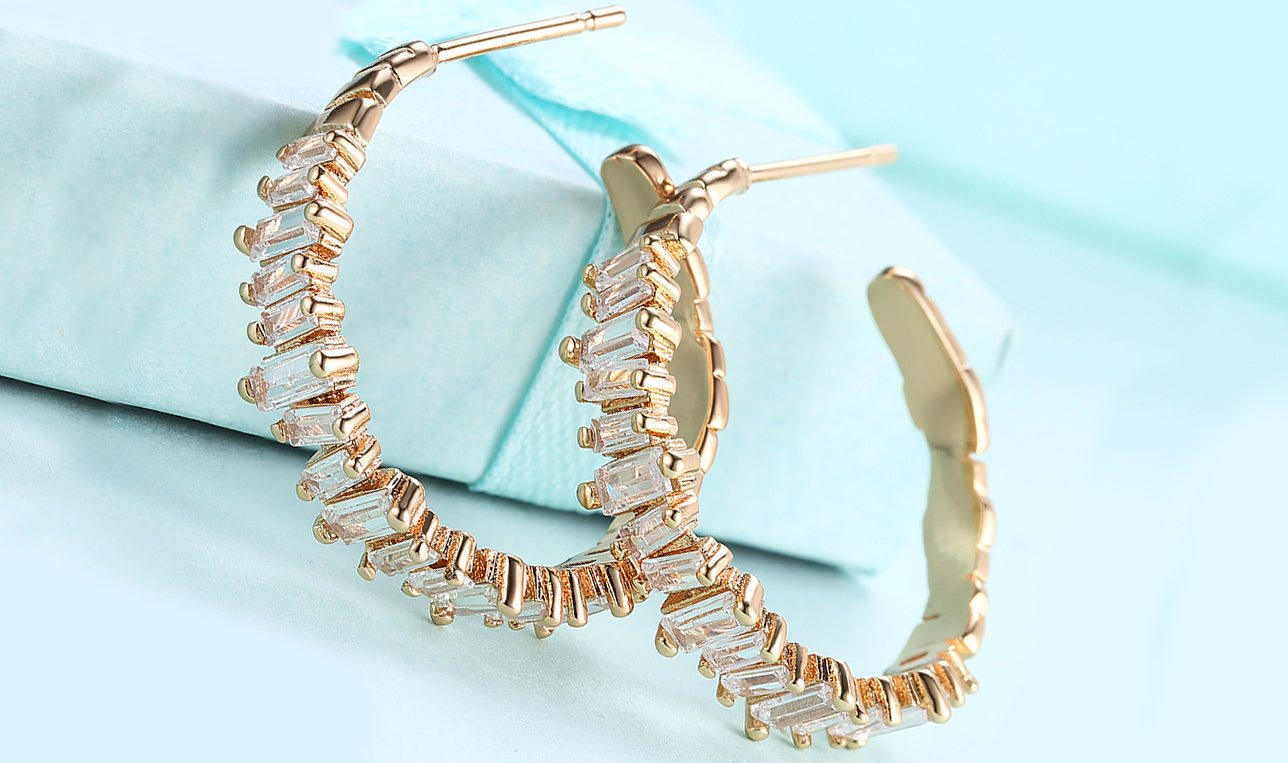 Elegant 14K gold plated asymmetrical earrings featuring emerald cut white elements stones, showcasing a modern design.