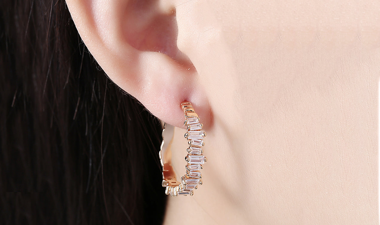 Elegant 14K gold plated asymmetrical earrings featuring emerald cut white elements stones, showcasing a modern design.