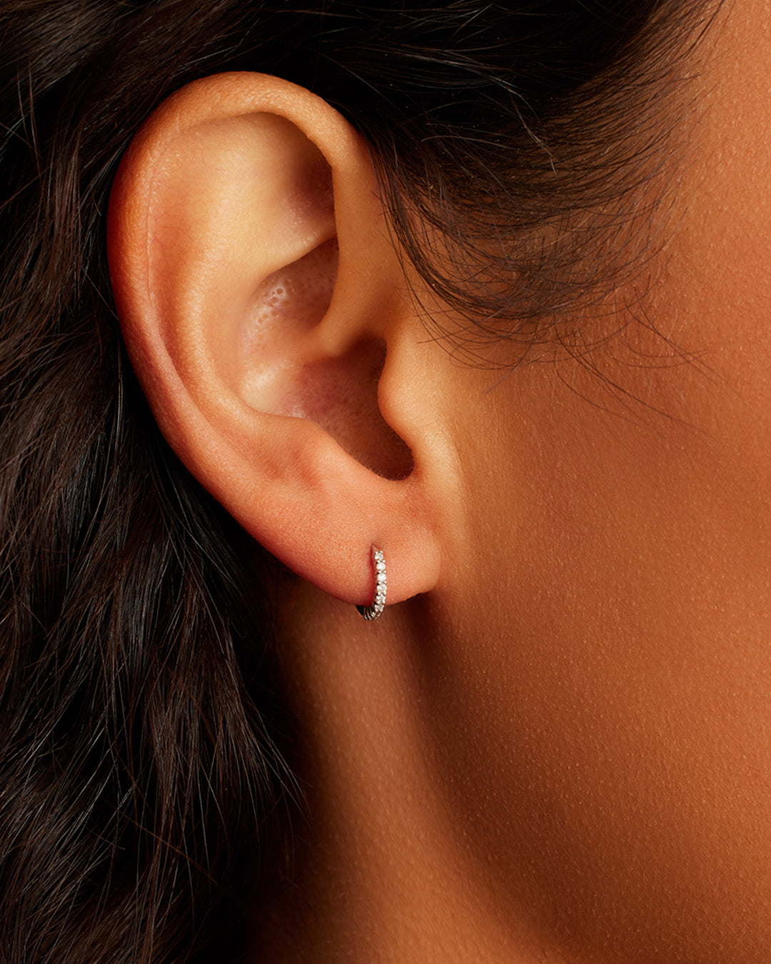 Elegant 14k white gold diamond pavé huggies showcasing intricate diamond setting and modern design.