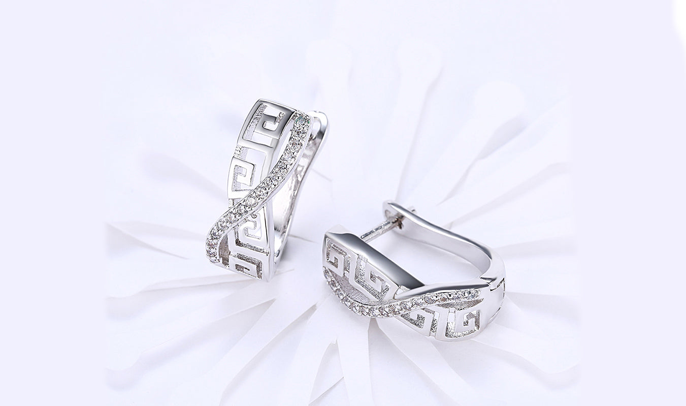 Elegant 14K white gold plated earrings featuring white sapphire stones in a Greek key design, showcasing a curved hinged style.