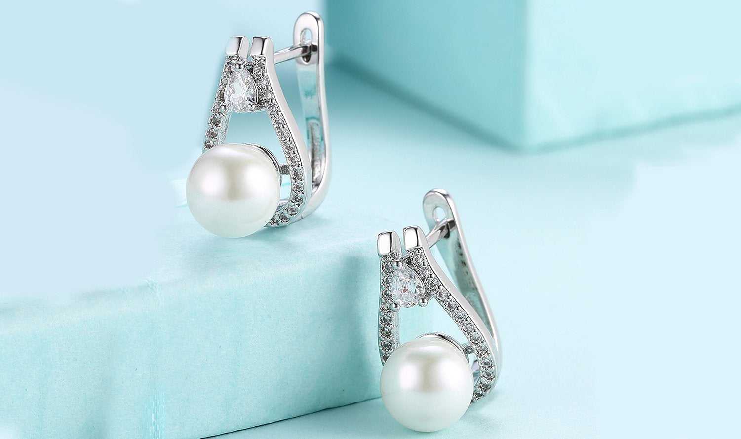 Elegant 14K white gold plated clip-on earrings featuring Austrian elements stones and freshwater pearls in a pear cut design.