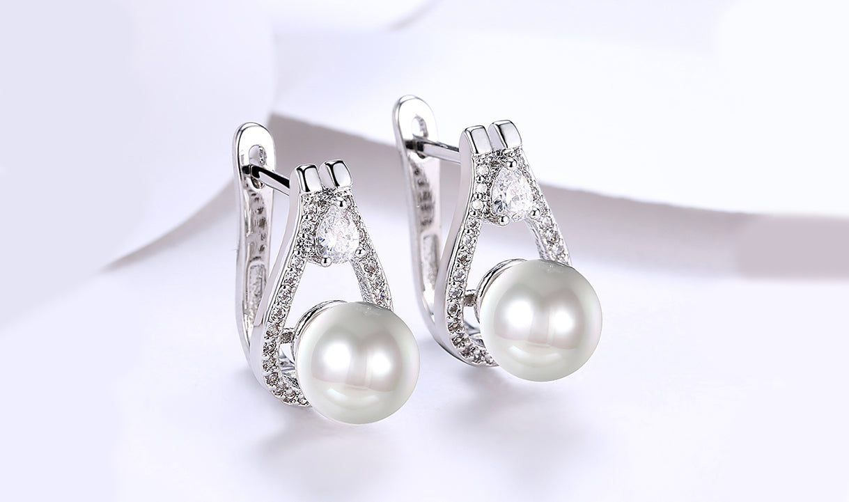 Elegant 14K white gold plated clip-on earrings featuring white sapphire stones and freshwater pearls in a pear cut design.