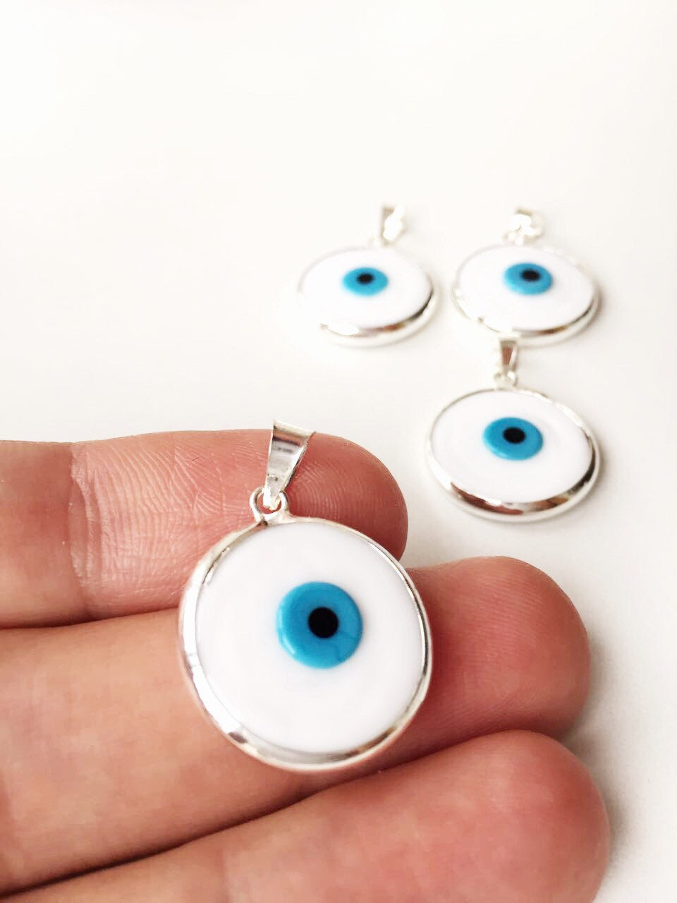 Two handmade white Murano glass evil eye pendants, featuring a traditional design, perfect for protection and style.