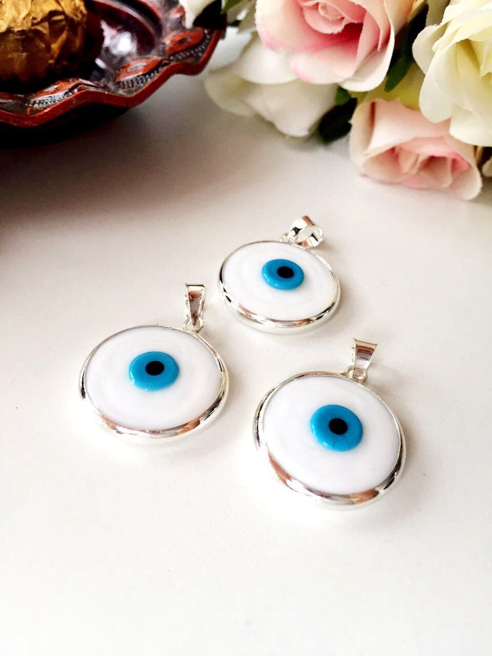 Two handmade white Murano glass evil eye pendants, featuring a traditional design, perfect for protection and style.