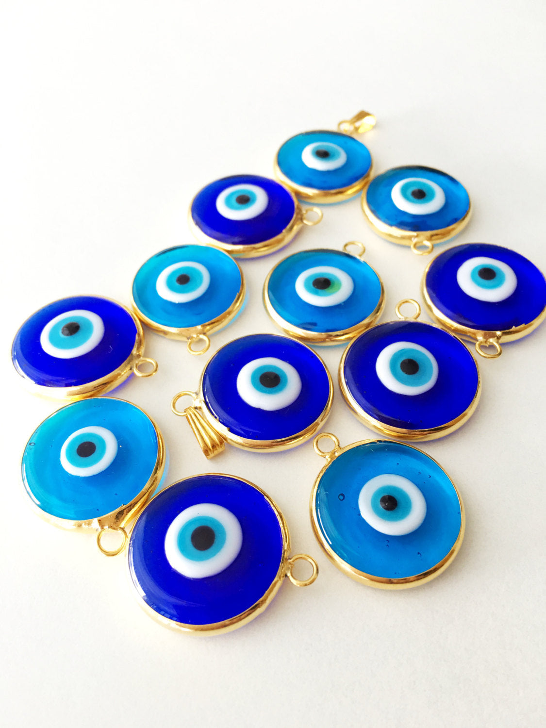 Two glass evil eye beads with gold plating, showcasing dark blue and opaque blue colors, perfect for jewelry making.