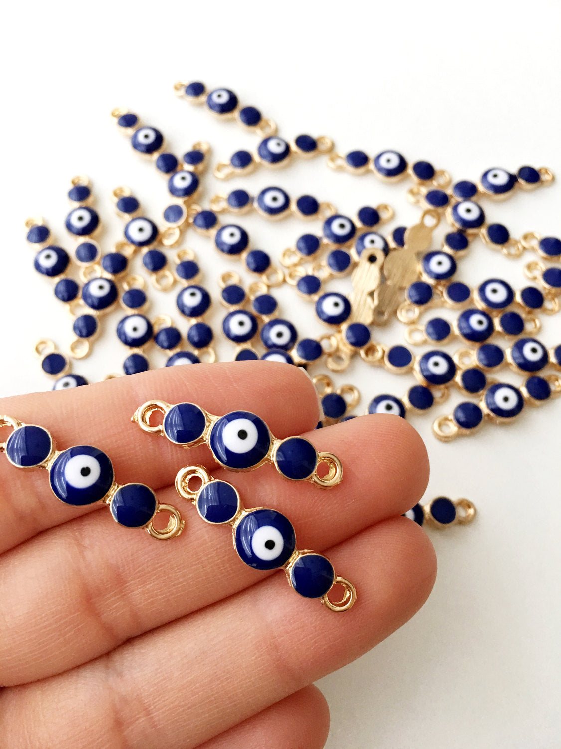 Three gold plated blue evil eye charms with dark blue and white enamel, perfect for jewelry making.