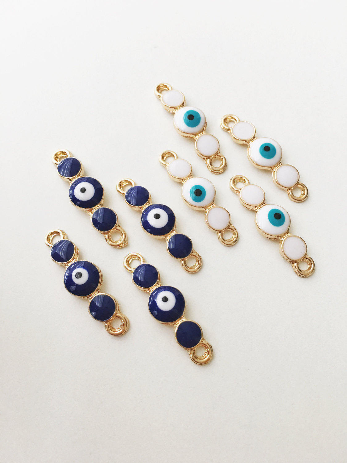 Three gold plated evil eye charms featuring white enamel and dark blue options, ideal for jewelry making.