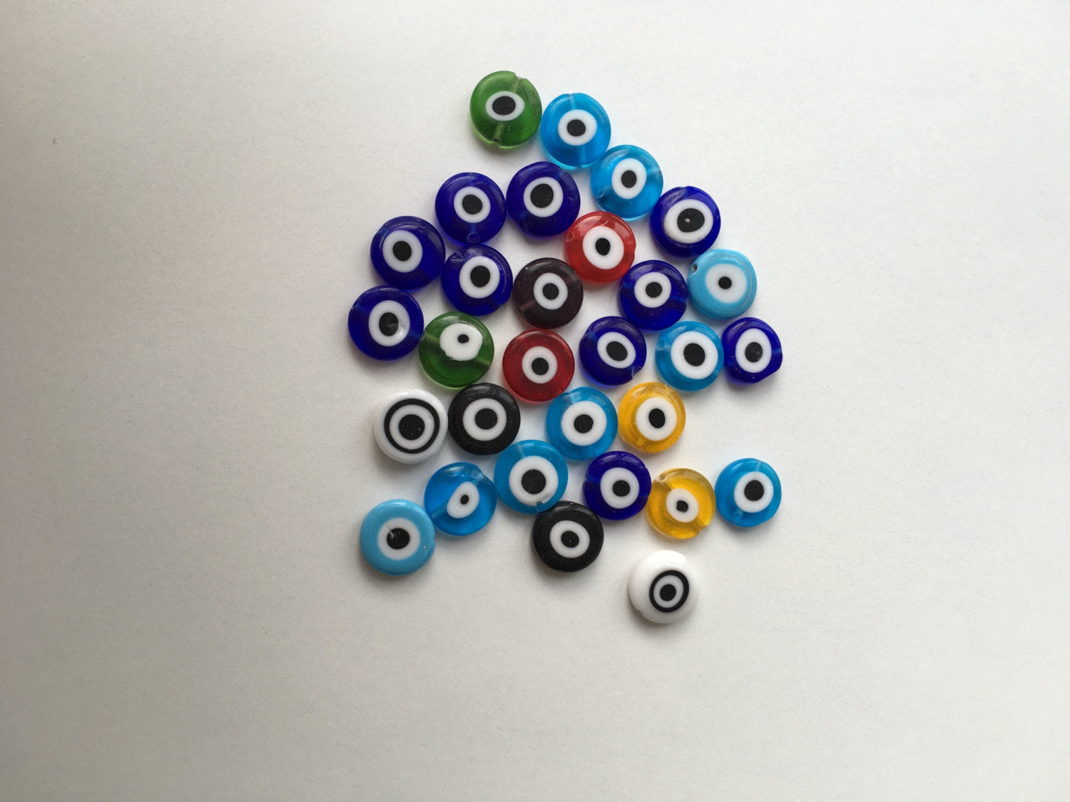 A vibrant assortment of 35 pcs 12mm flat Glass Evil Eye Beads in mixed colors, showcasing their unique designs and craftsmanship.
