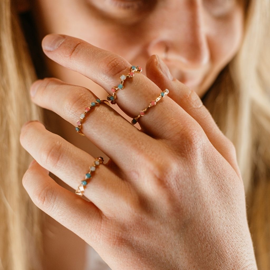 A set of four gold stackable rings featuring intricate tribal designs and vibrant multi-coloured stones, perfect for bohemian style.