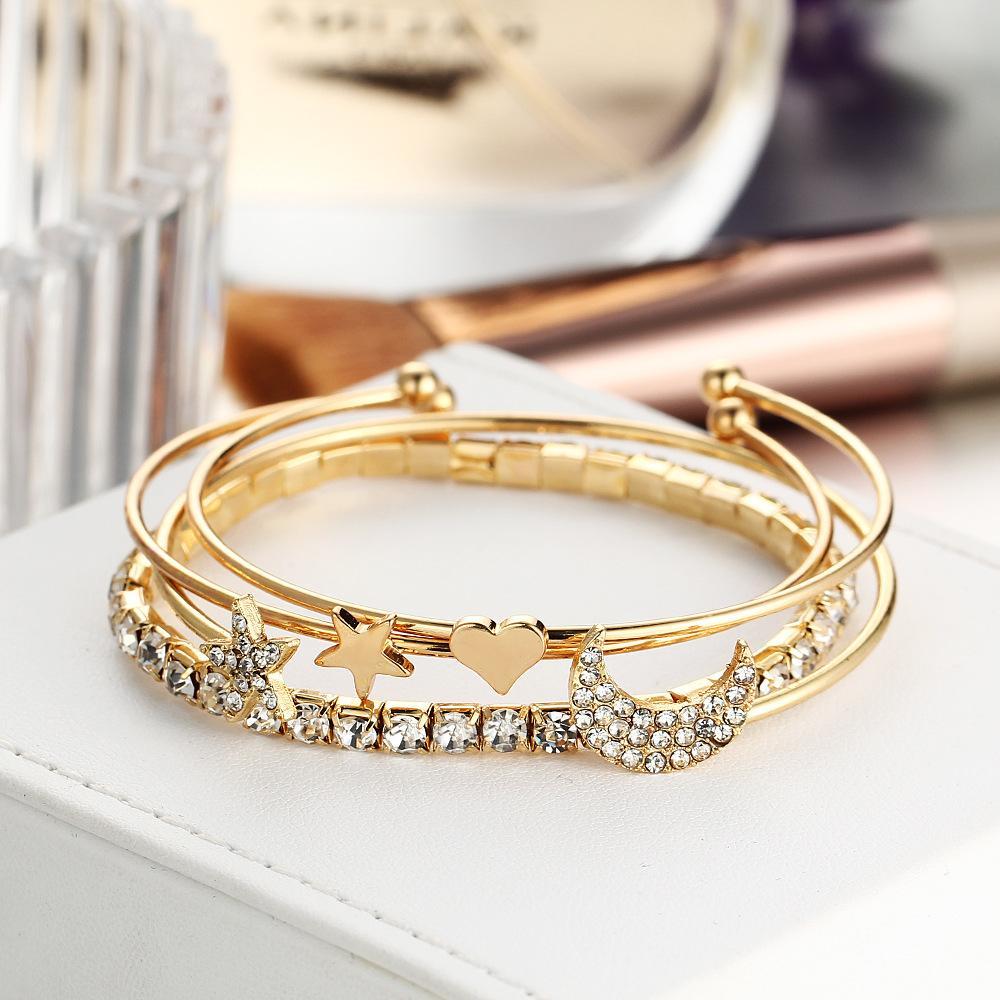 A luxurious 4 Piece Celestial Bangle Set featuring sparkling crystals and 18K gold plating, elegantly displayed on a soft surface.