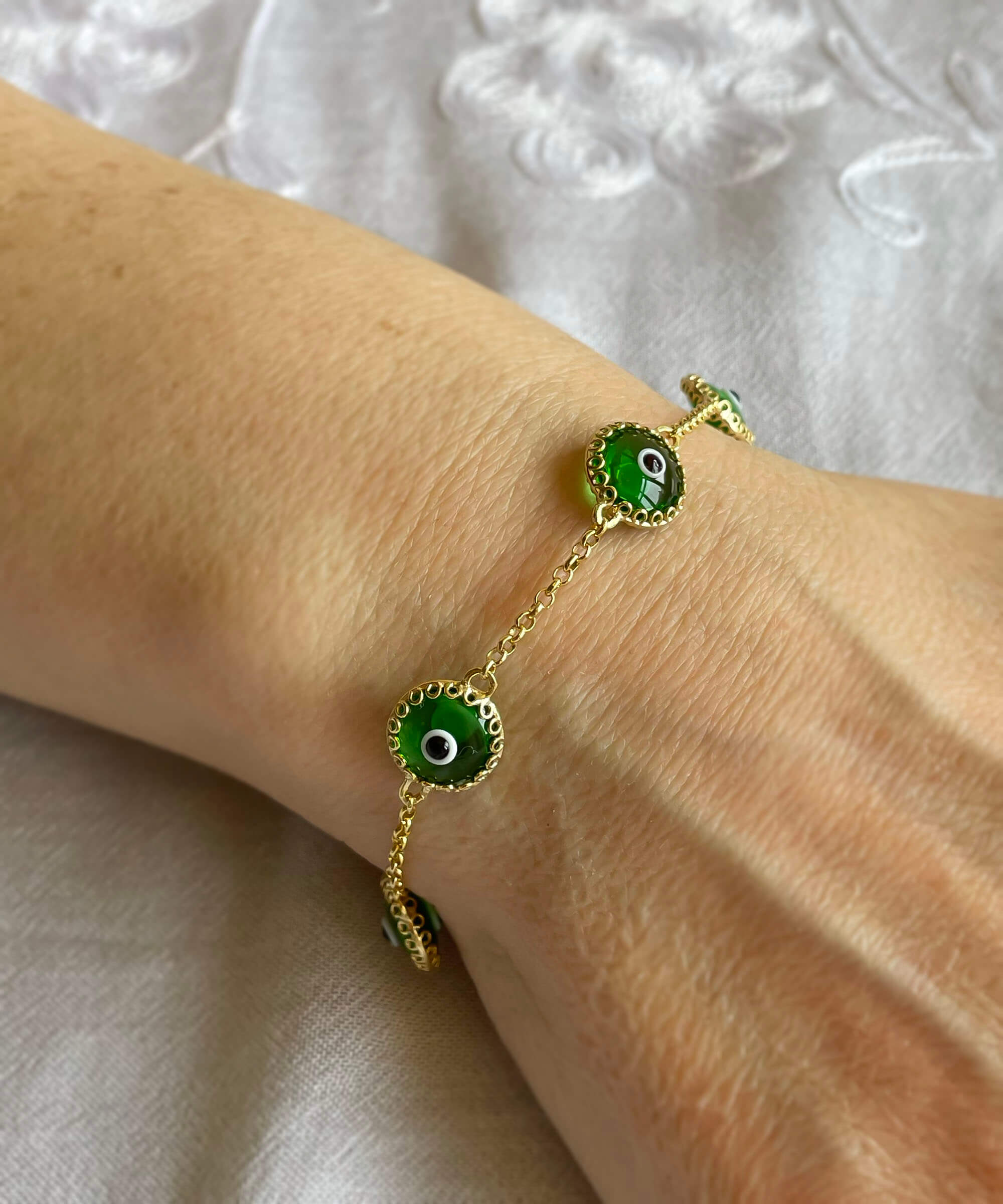 Mint green evil eye bracelet featuring five beads on a gold plated sterling silver link chain, secured with a lobster claw clasp.
