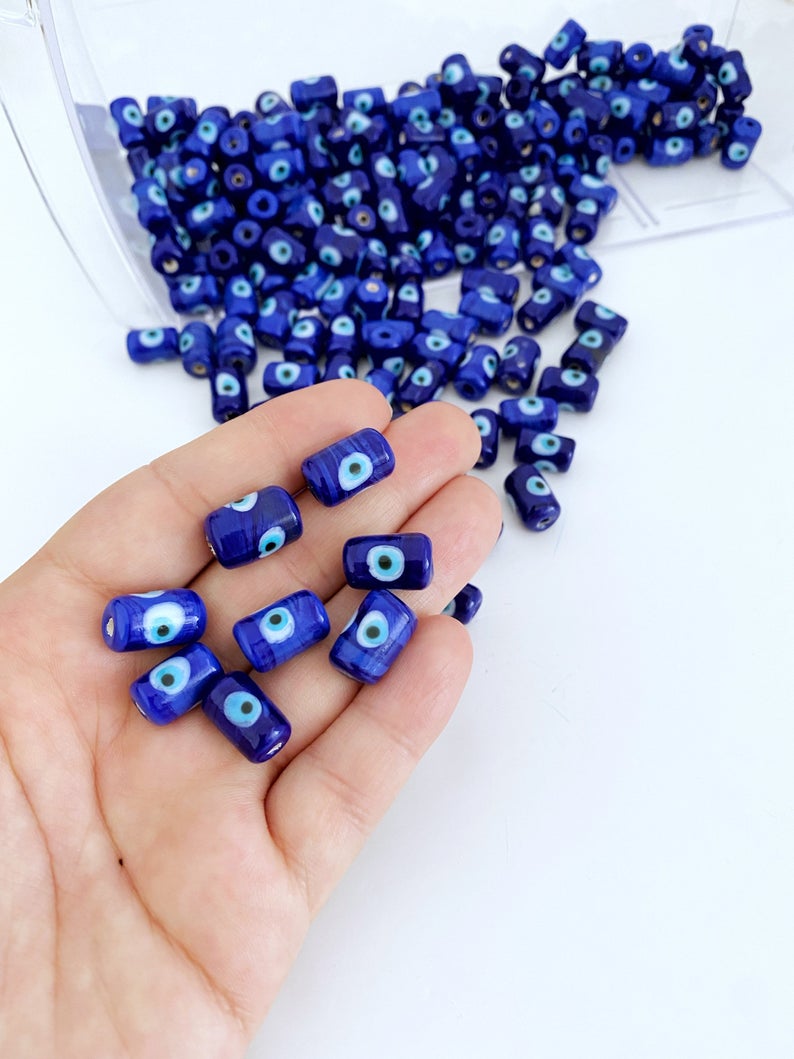 Five blue evil eye tube beads made of Murano glass, showcasing intricate designs and vibrant colors, ideal for jewelry making.