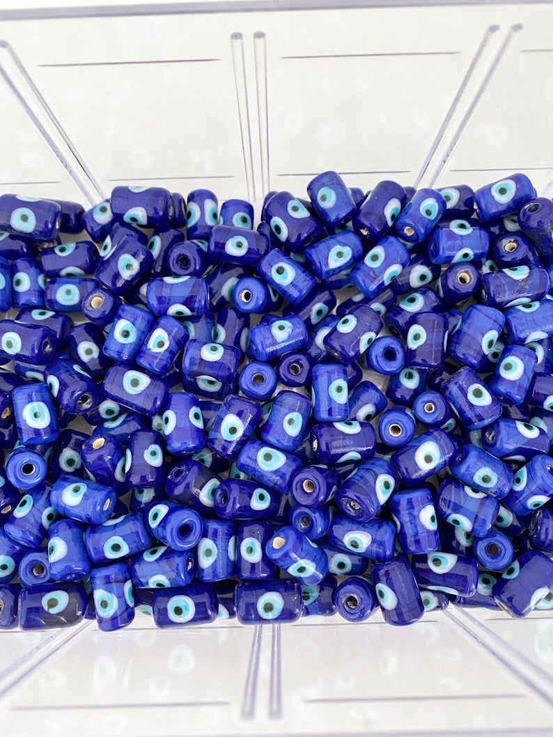 Five blue evil eye tube beads made of Murano glass, showcasing intricate designs and vibrant colors, ideal for jewelry making.
