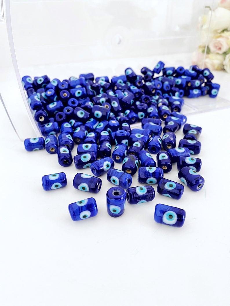 Five blue evil eye tube beads made of Murano glass, showcasing intricate designs and vibrant colors, ideal for jewelry making.
