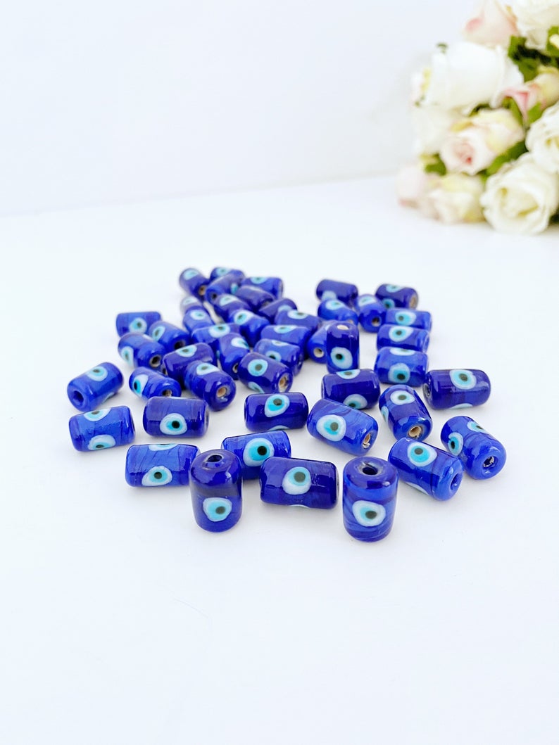 Five blue evil eye tube beads made of Murano glass, showcasing intricate designs and vibrant colors, ideal for jewelry making.