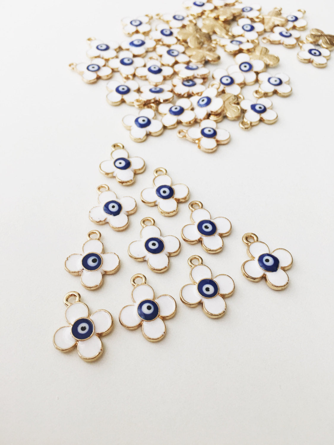 Five 22K matte gold plated clover evil eye charms, featuring a four leaf design and white evil eye pendant, displayed elegantly.