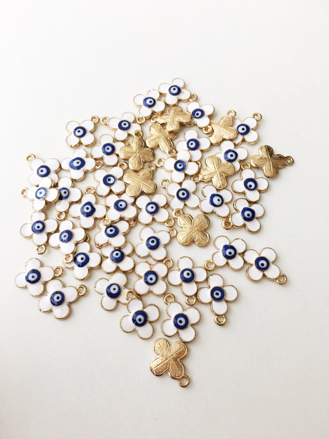 Five 22K matte gold plated clover evil eye charms, featuring a four leaf design and white evil eye pendant, displayed elegantly.