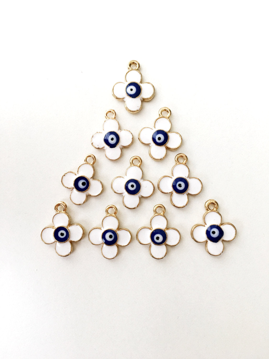 Five 22K matte gold plated clover evil eye charms, featuring a four leaf design and white evil eye pendant, displayed elegantly.