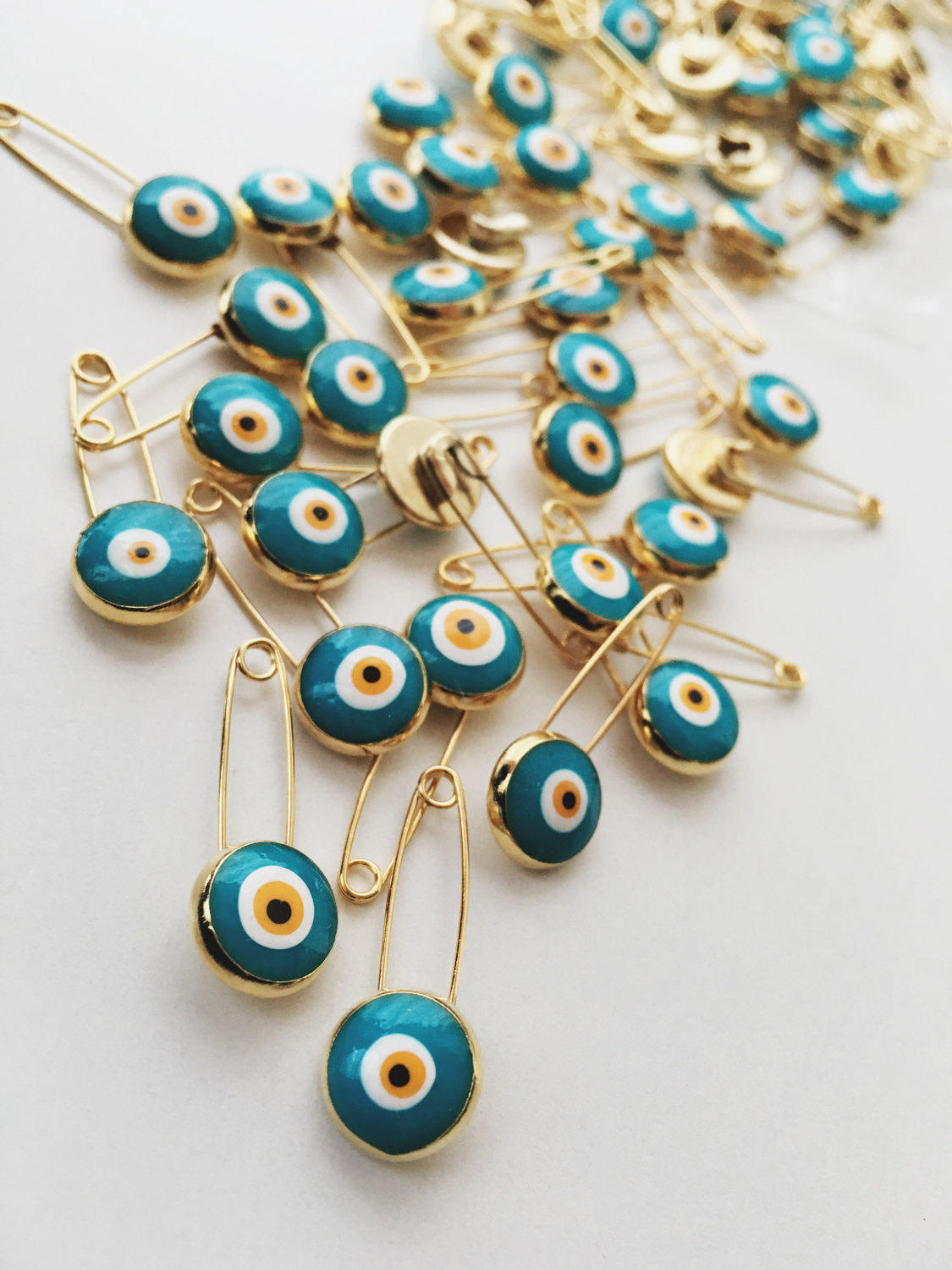 Set of 5 green evil eye safety pins with gold plating, featuring big enamel evil eye charms for baby protection.