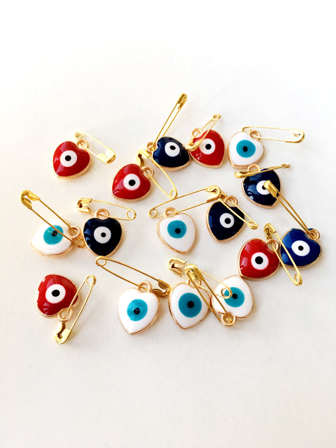 Set of 5 heart-shaped evil eye safety pins in various colors, featuring a big enamel evil eye design on a gold plated safety pin.