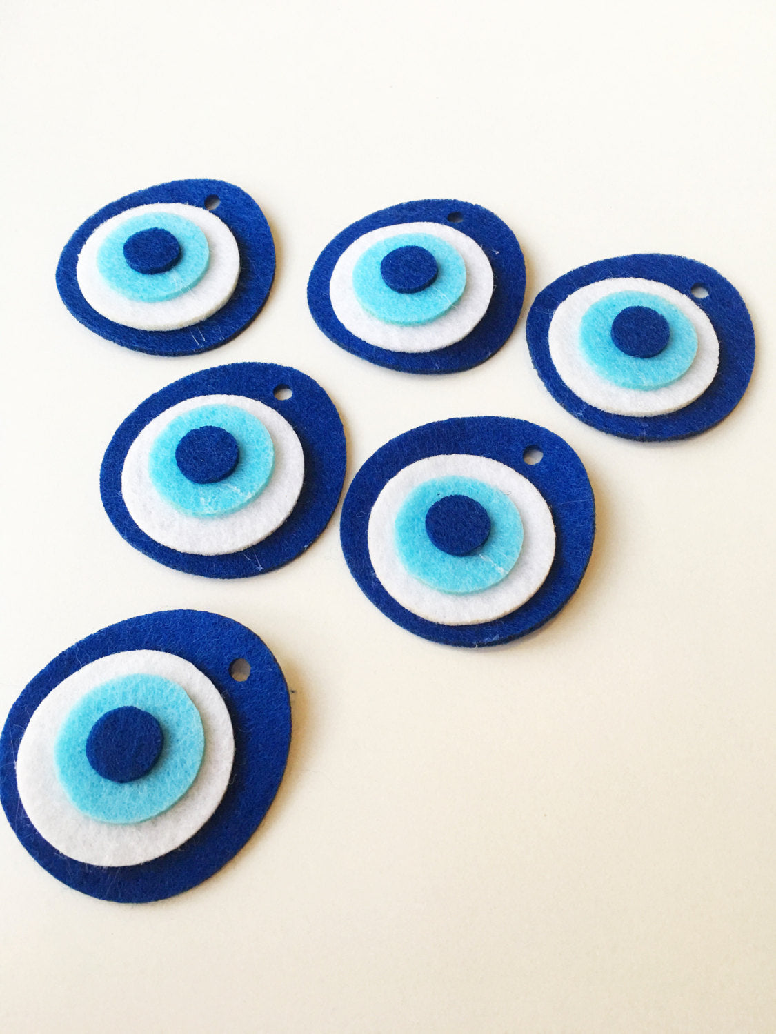 Five handmade felted evil eye beads, each 4cm, featuring vibrant colors and a top hole for easy stringing.