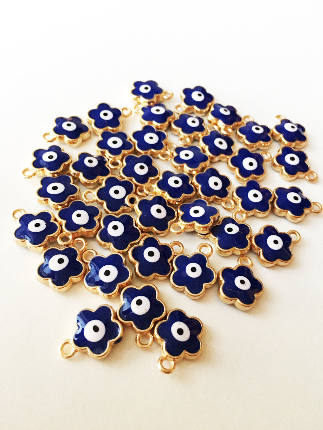 Five elegant four leaf clover evil eye pendants in pink, turquoise, and dark blue, showcasing their 22K gold plating and unique design.