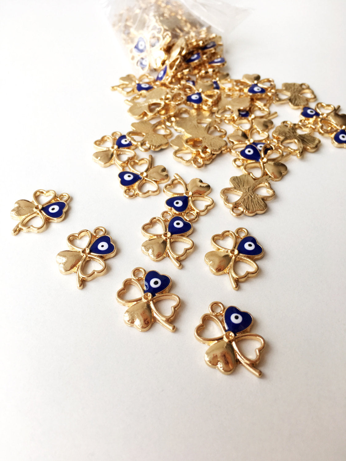 Five gold plated four leaf clover evil eye pendants, showcasing intricate designs and a protective charm.