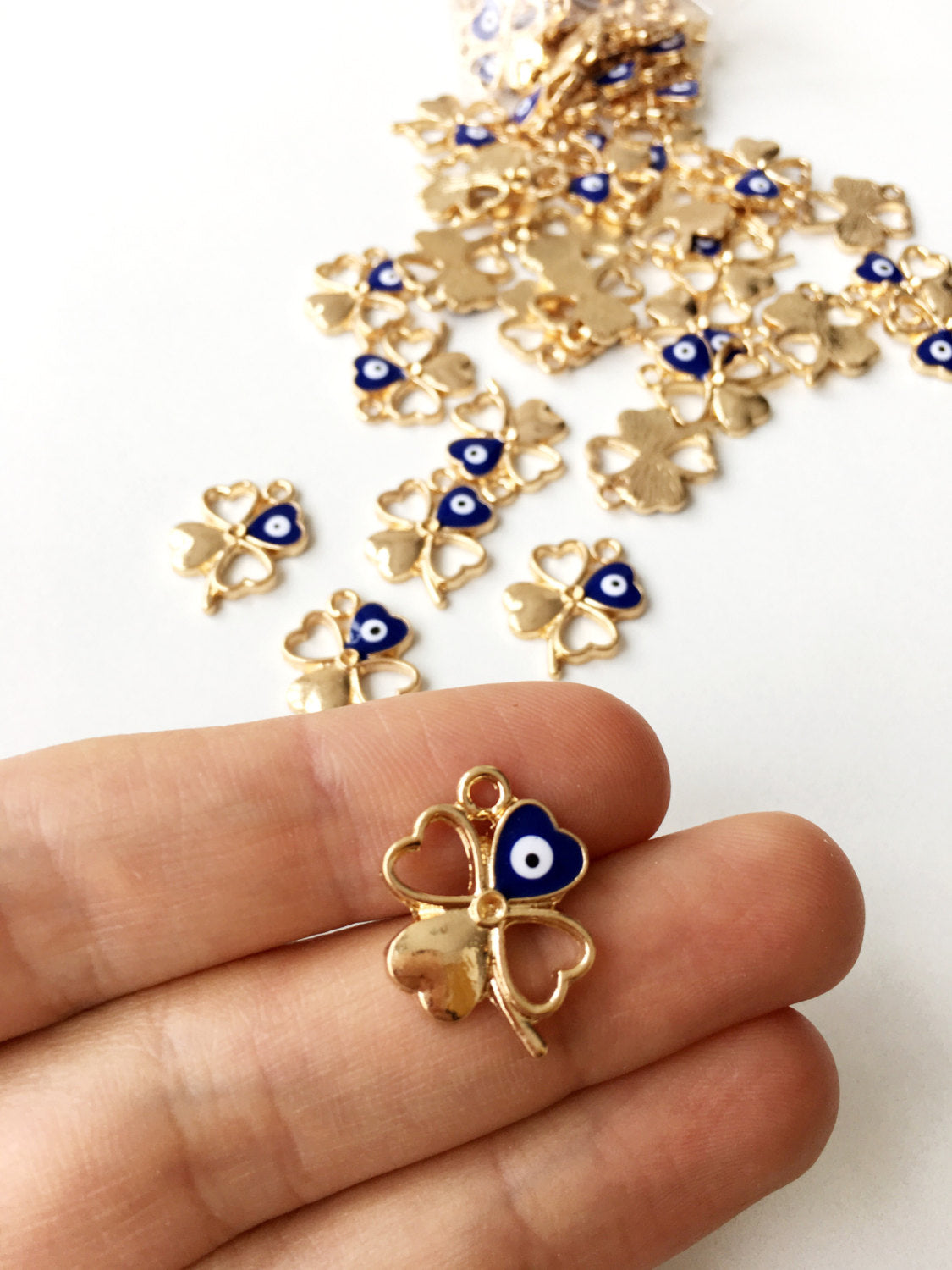 Five gold plated four leaf clover evil eye pendants, showcasing intricate designs and a protective charm.